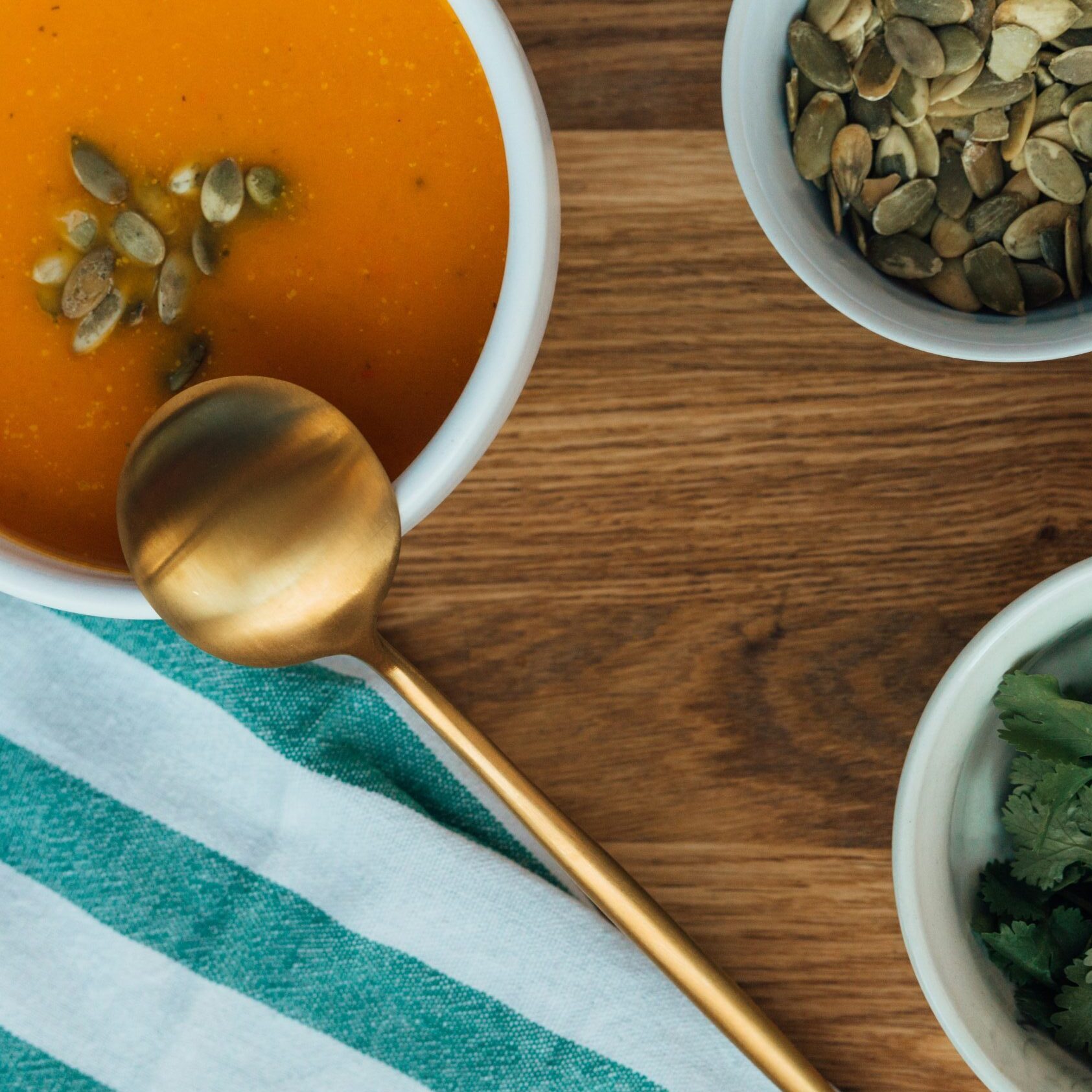 Pumpkin Soup in a bowl and herbs in smaller bowls